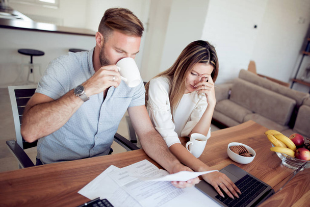 Young couple going through their financial records in their home. - Foto, Bild
