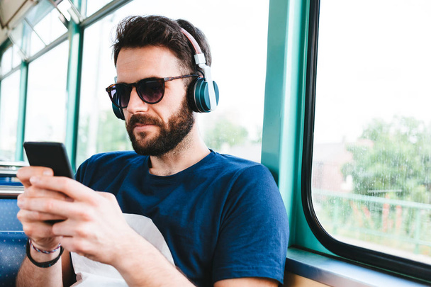 Junger Mann fährt in öffentlichen Verkehrsmitteln und hört Musik - Foto, Bild