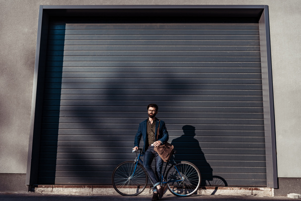 handsome bearded man in glasses and cap holding bicycle - Photo, Image