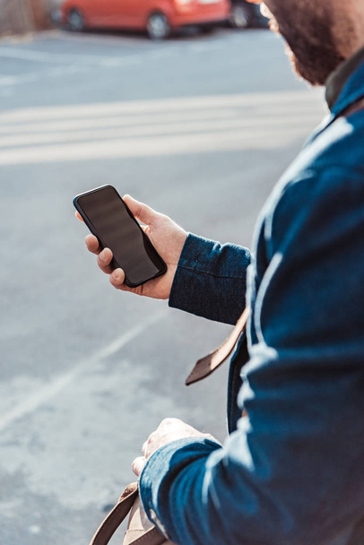  cropped view of bearded man in blue jacket holding smartphone with blank screen - Foto, Bild