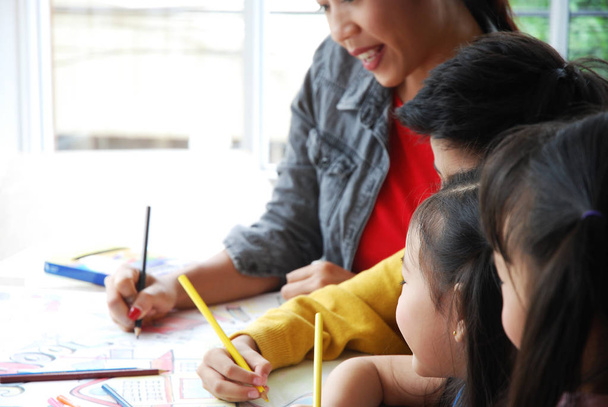 Opettajat opettavat valkoiselle paperille piirtämistä kolmelle lapselle viikonloppuna. Taustan hämärtyminen
 - Valokuva, kuva