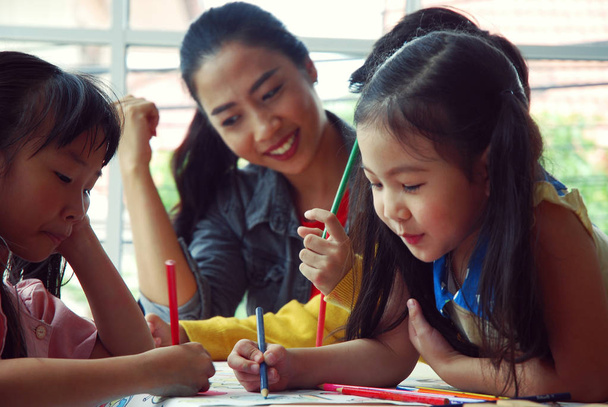 Lehrer bringen drei Kindern am Ferienwochenende das Zeichnen auf weißem Papier bei. Hintergrundunschärfe - Foto, Bild