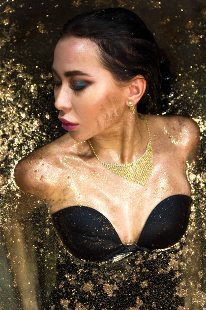 Sexy brunette woman in black kombi dress posing in a bath in sequins - Fotografie, Obrázek