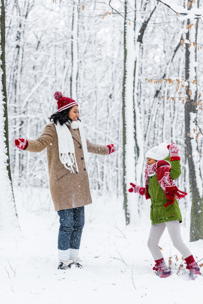 cheerful african american woman and preteen daughter having fun in winter park - Photo, image
