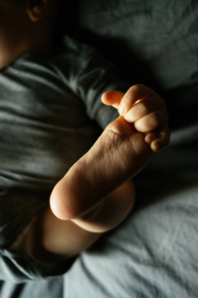 Close-up of a child holding onto his leg - Foto, afbeelding
