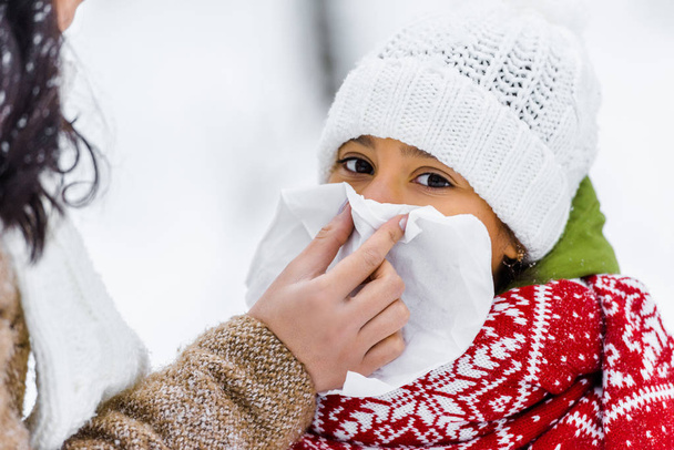 przycięte widzenia Matki wycieranie nosa serwetka z córka w winter park  - Zdjęcie, obraz