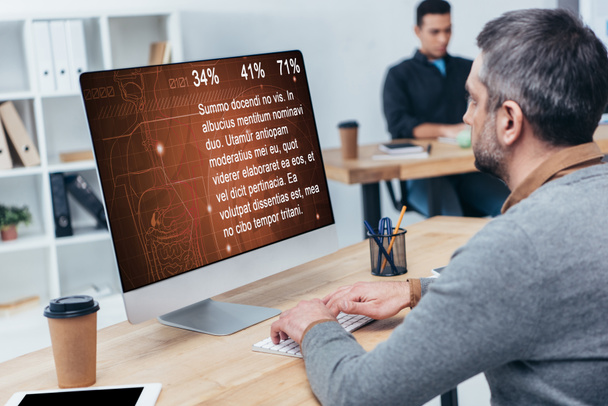 zakenman desktopcomputer met statistieken op scherm in kantoor - Foto, afbeelding