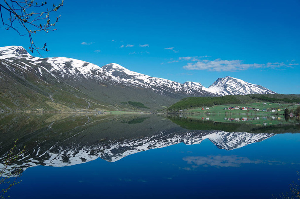 Noorwegen prachtige lente landschap. Weerspiegeling van de bergen in kalm water van fjord - Foto, afbeelding