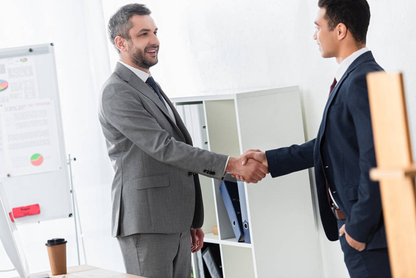 happy businessman in formal wear shaking hands and smiling each other in office  - Foto, immagini