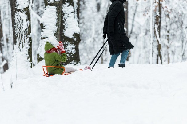  Tochter mit Mutter auf Schlitten im verschneiten Wald - Foto, Bild
