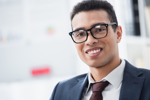 portrait of handsome young businessman in eyeglasses smiling at camera - Foto, afbeelding