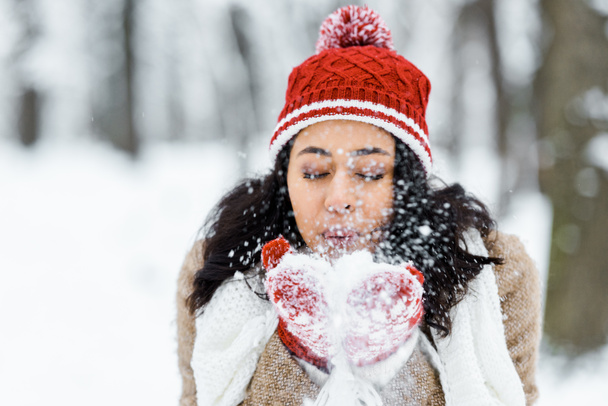 attractive african american woman blowing snow in park in winter forest - Photo, Image