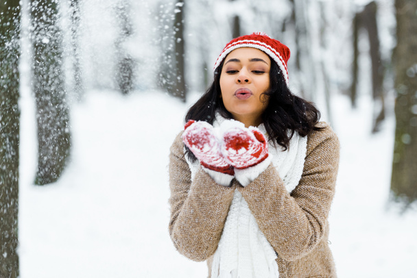 beautiful african american woman blowing snow in winter forest - Photo, Image
