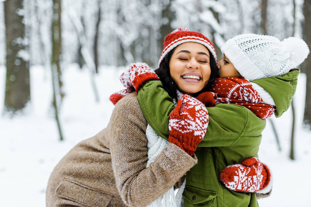 cute african american daughter hugging mother in winter forest - Foto, immagini