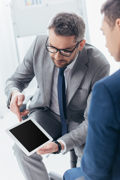 tiro cortado de empresário em óculos mostrando tablet digital com tela em branco para colega do sexo masculino no escritório
 - Foto, Imagem