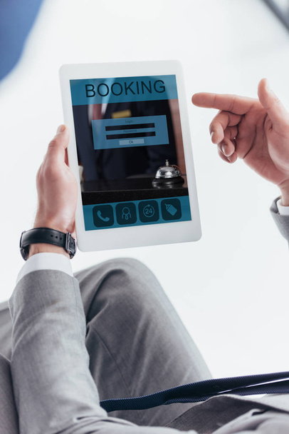 partial view of businessman using digital tablet with booking application on screen - Photo, Image
