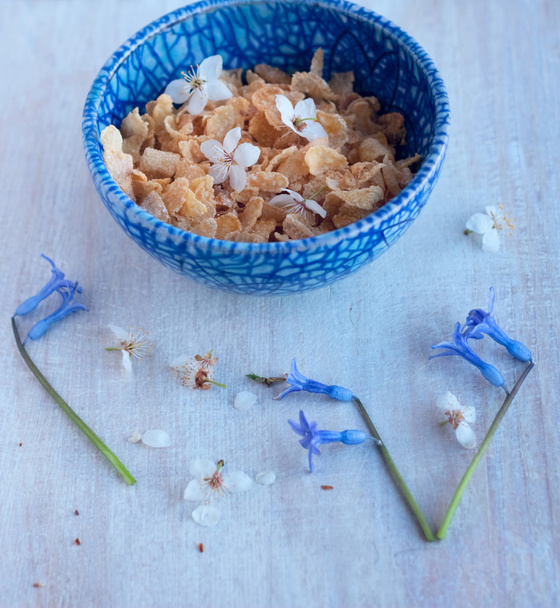 corn flakes in a blue bowl and flowers - Photo, Image