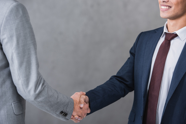 cropped shot of businessmen in formal wear shaking hands on grey - Photo, Image