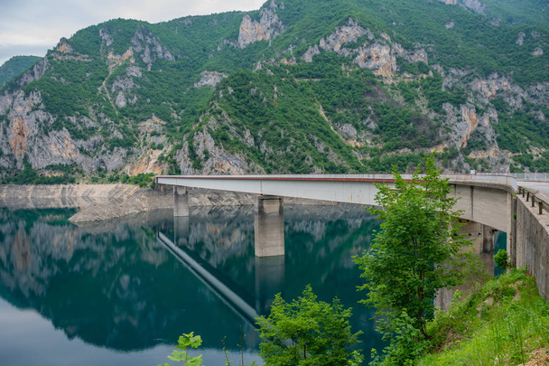 μεγάλη μεταλλική γέφυρα που διασχίζονται από γραφικά ορεινά λίμνη - Φωτογραφία, εικόνα