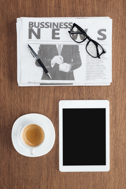 一杯のコーヒー、空白の画面と木製のテーブルの上のビジネス新聞をタブレットの立面図 - 写真・画像