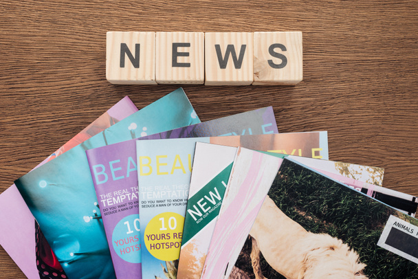 vista superior de cubos de madeira com notícias de palavras e revistas em mesa de madeira
 - Foto, Imagem