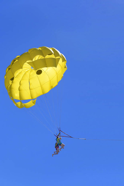Pareja activa joven disfrutando de volar con paracaídas, actividad extrema de parasailing
 - Foto, Imagen