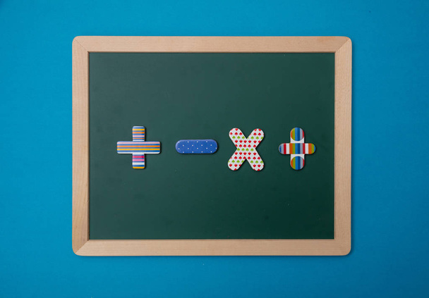 Mathematik, Schulkonzept. grüne Kreidetafel mit Holzrahmen, bunte Einsatzschilder, blauer Hintergrund - Foto, Bild
