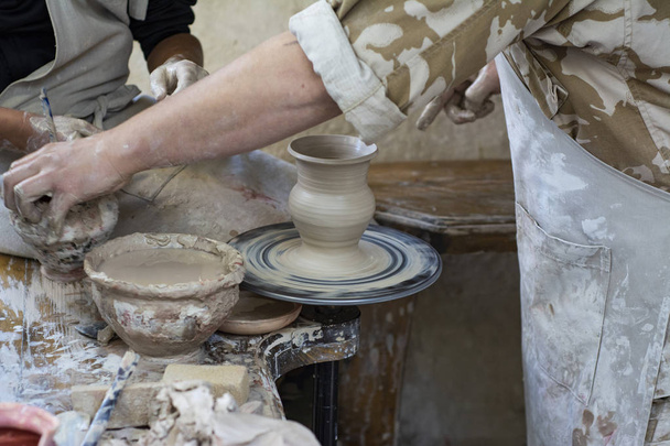 陶芸家は、子供に粘土の鍋の作り方を教えています。. - 写真・画像