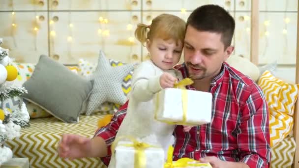 cute little girl with young father unpack gift boxes near Christmas tree at home - Materiaali, video