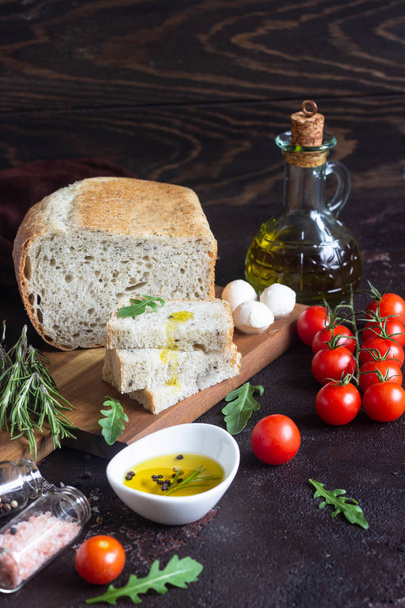 Bread, mozzarella, cherry tomatoes, olive oil, arugula and rosemary. Sandwich recipe Copy space.  - Фото, зображення