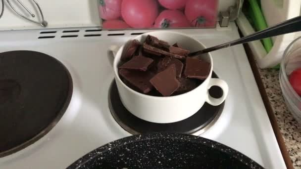 Pieces of black and white chocolate in a bowl on the stove. The chocolate is melted in a water bath to make a dessert. - Séquence, vidéo