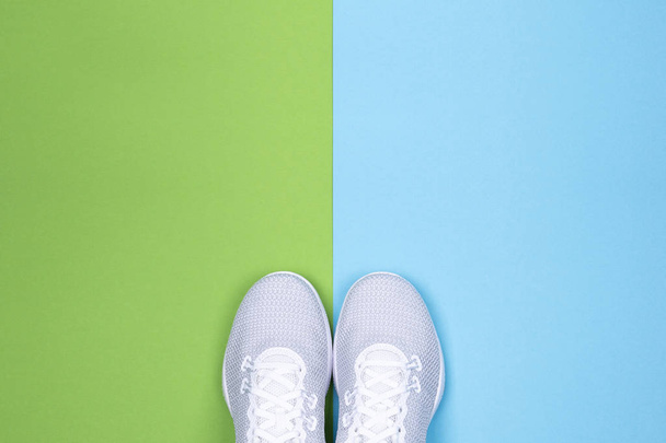 Λευκά αθλητικά παπούτσια σε μπλε και πράσινο φόντο.  - Φωτογραφία, εικόνα