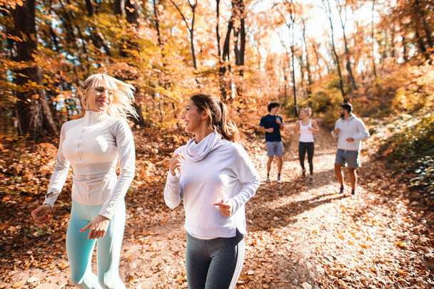 Malá skupina happy přátelé běží na podzim v lese. - Fotografie, Obrázek