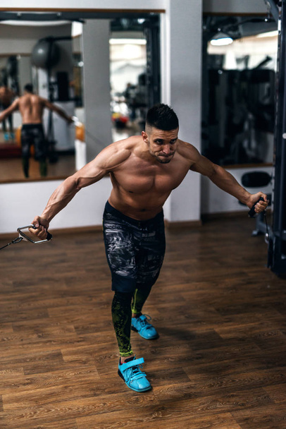 bodybuilder torse nu fort faisant des exercices avec l'équipement d'exercice. Gym intérieur
. - Photo, image