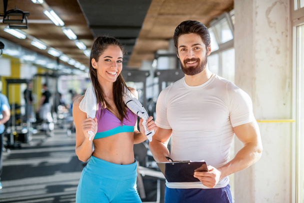 Immagine di personal fitness trainer e il suo cliente femminile in palestra in posa davanti alla telecamera
. - Foto, immagini