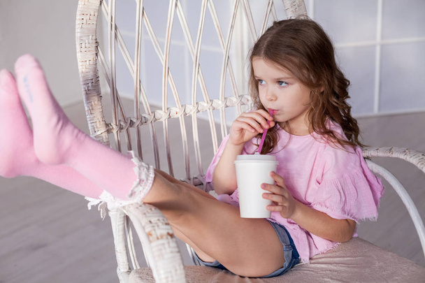 красивая маленькая девочка пьет молочный коктейль через соломинку
 - Фото, изображение