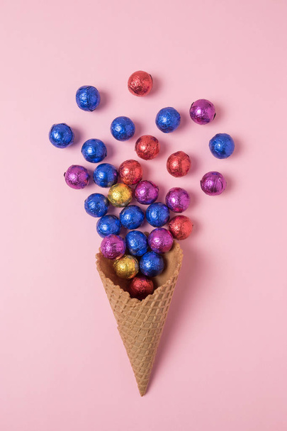 Ice cream cone with colored candyes on pink background. Minimal holiday concept. - Φωτογραφία, εικόνα