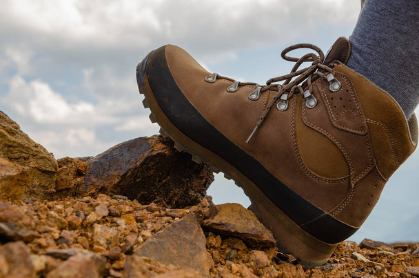 Pied en chaussure de randonnée sur une pierre et une surface de terre orange
 - Photo, image