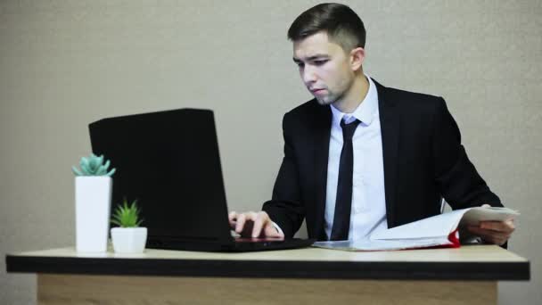 Young businessman working at office, typing on a laptop. - Кадры, видео
