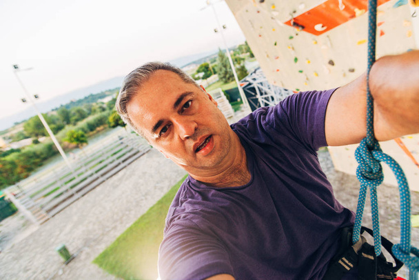 Hombre con soga, trepando sobre un muro de escalada muy alto
 - Foto, Imagen