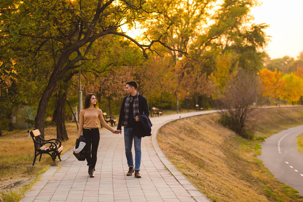 Couple walks in the park at sunset feeling loved and happy. - Foto, afbeelding