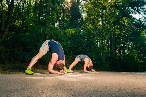 Athletic couple stretching in nature after exercising - Photo, Image