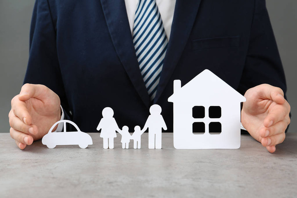 Man with cutout paper family, house and car at table, closeup. Life insurance concept - Photo, Image