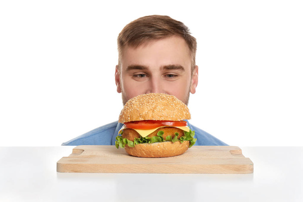 Young man eating tasty burger on color background - Photo, Image