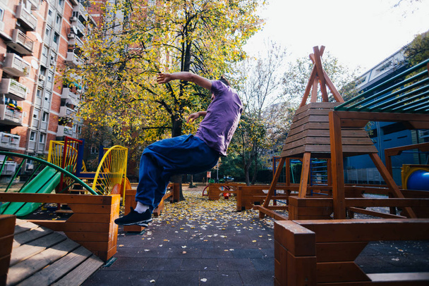 Молодий хлопець паркур робить трюки, перевертається і займається спортом на дитячому майданчику
. - Фото, зображення