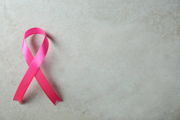 Pink ribbon and space for text on gray background, top view. Breast cancer awareness concept - Фото, зображення