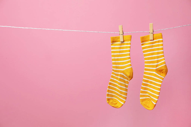 Cute socks on laundry line against color background. Space for text - Fotoğraf, Görsel