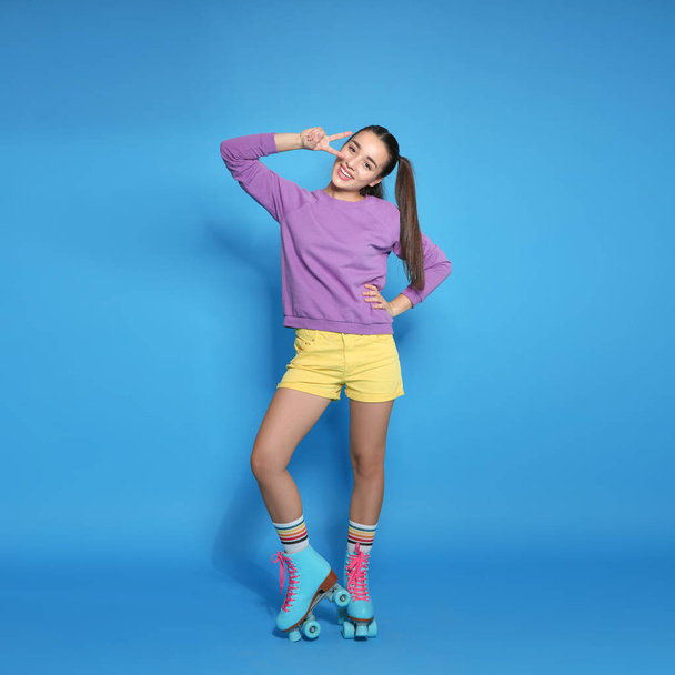 Full length portrait of young woman with roller skates on color background - Valokuva, kuva