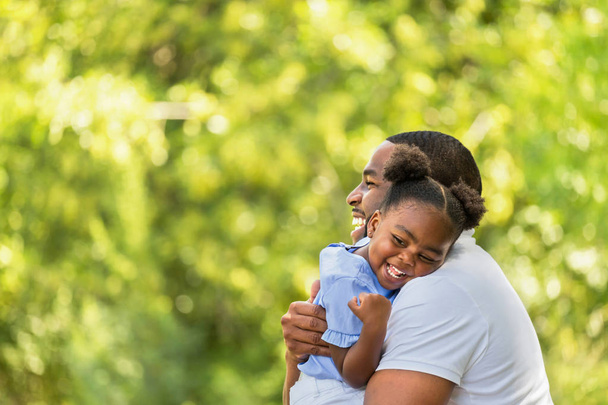 African American father hugging and holding his little girl. - 写真・画像