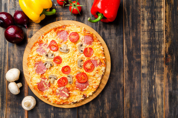 hausgemachte Pizza mit Tomaten und Pilzen auf einem Holztisch mit Gemüse - Foto, Bild